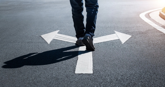 Man walking on road with two direction arrow
